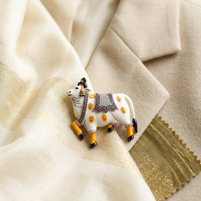 Decorative 925 silver pichwai cow vastra moissanite diamond enamel brooch figurine on a textured fabric background