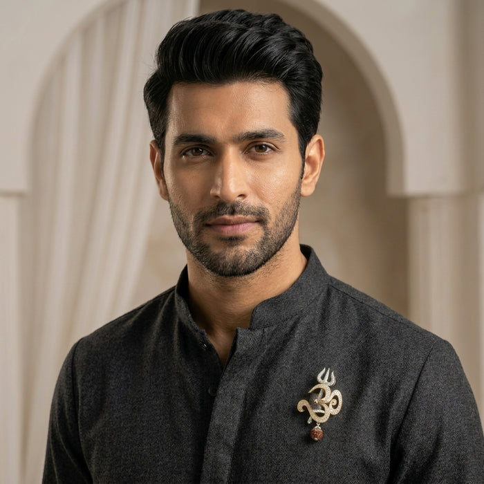 Man wearing a dark traditional outfit with a 925 silver OM moissanite brooch in an indoor setting