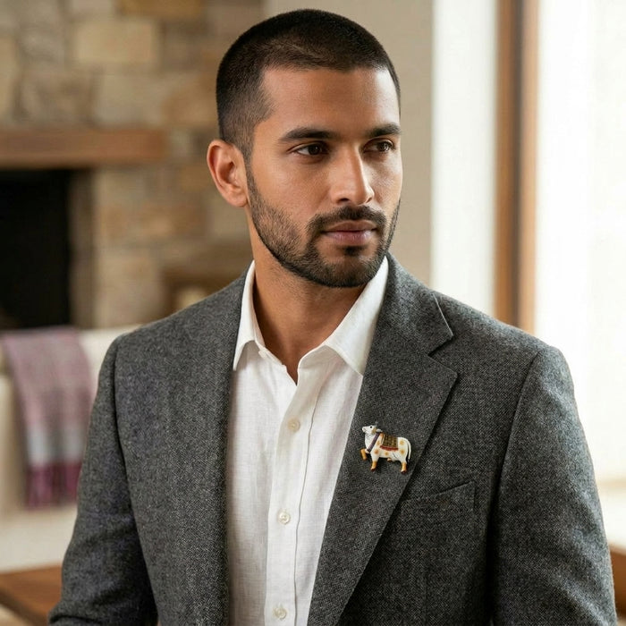 Man wearing a gray blazer with a 925 silver pichwai cow vastra enamel brooch pin indoors