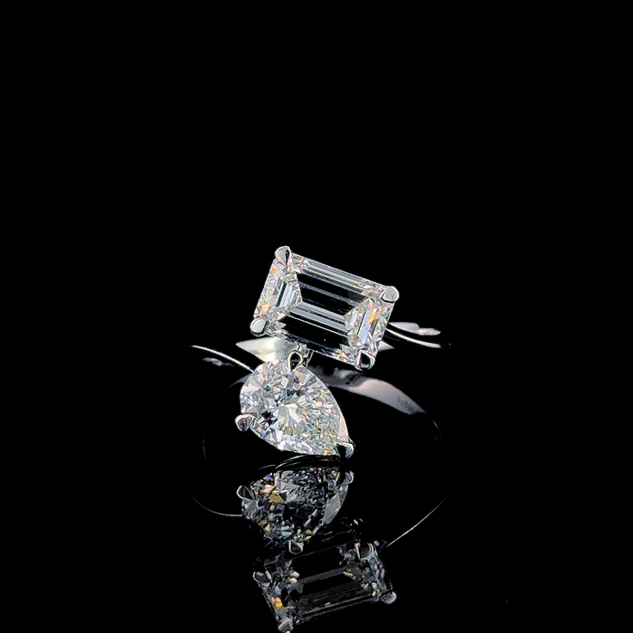 Emerald and pear cut toi et moi ring, angled view showing both stones
